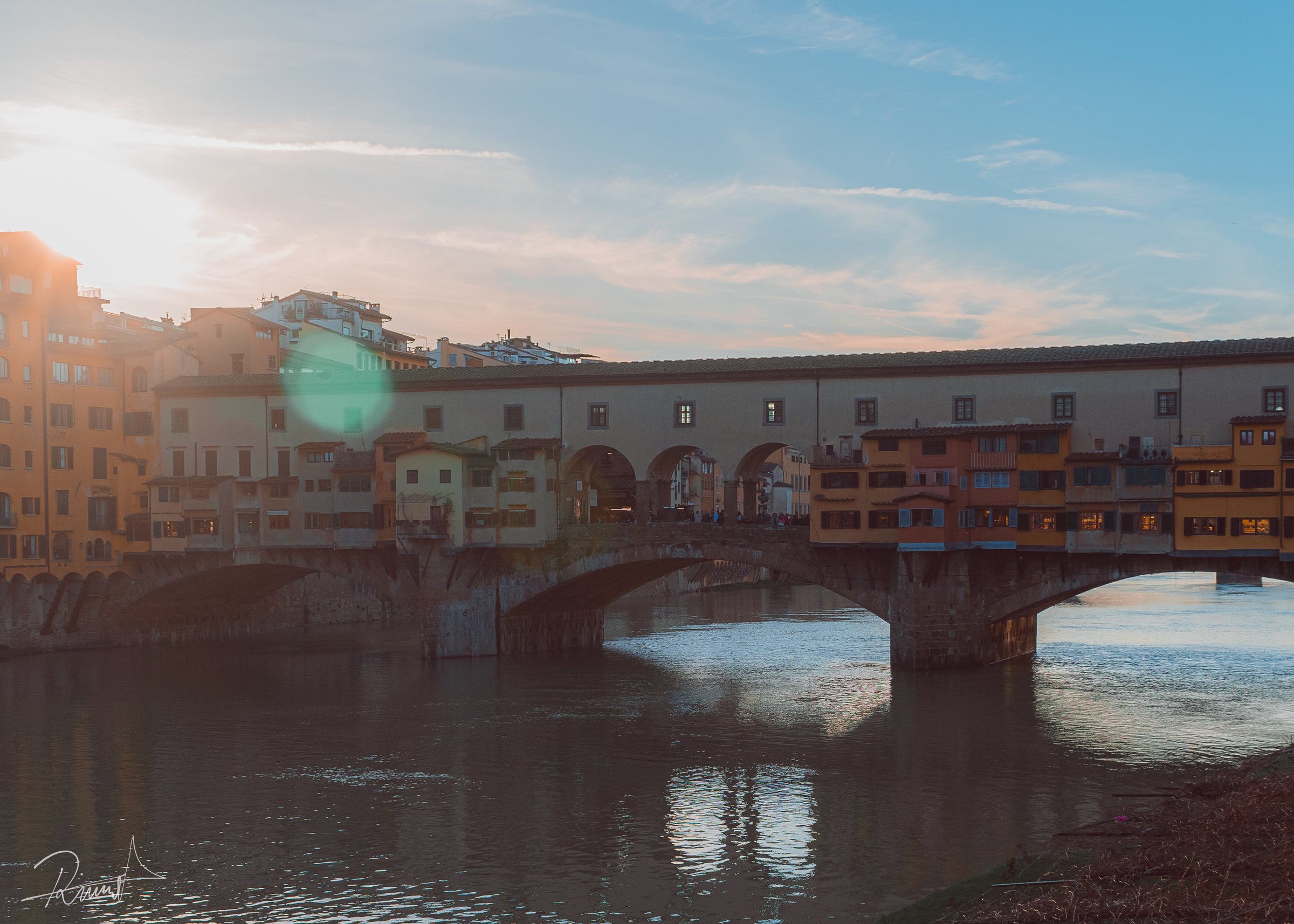 Puente y edificios reflejados en un río al atardecer